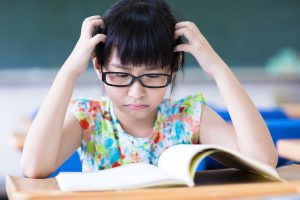 Young girl seeming to struggle while reading