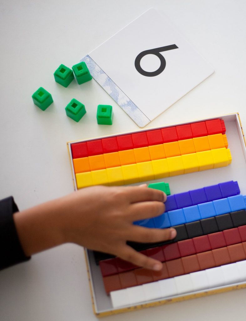 Child using counting cubes and a number card to build numeracy skills