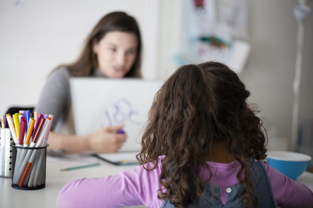 Instructor working one-on-one with a young student on letter formation during a literacy lesson